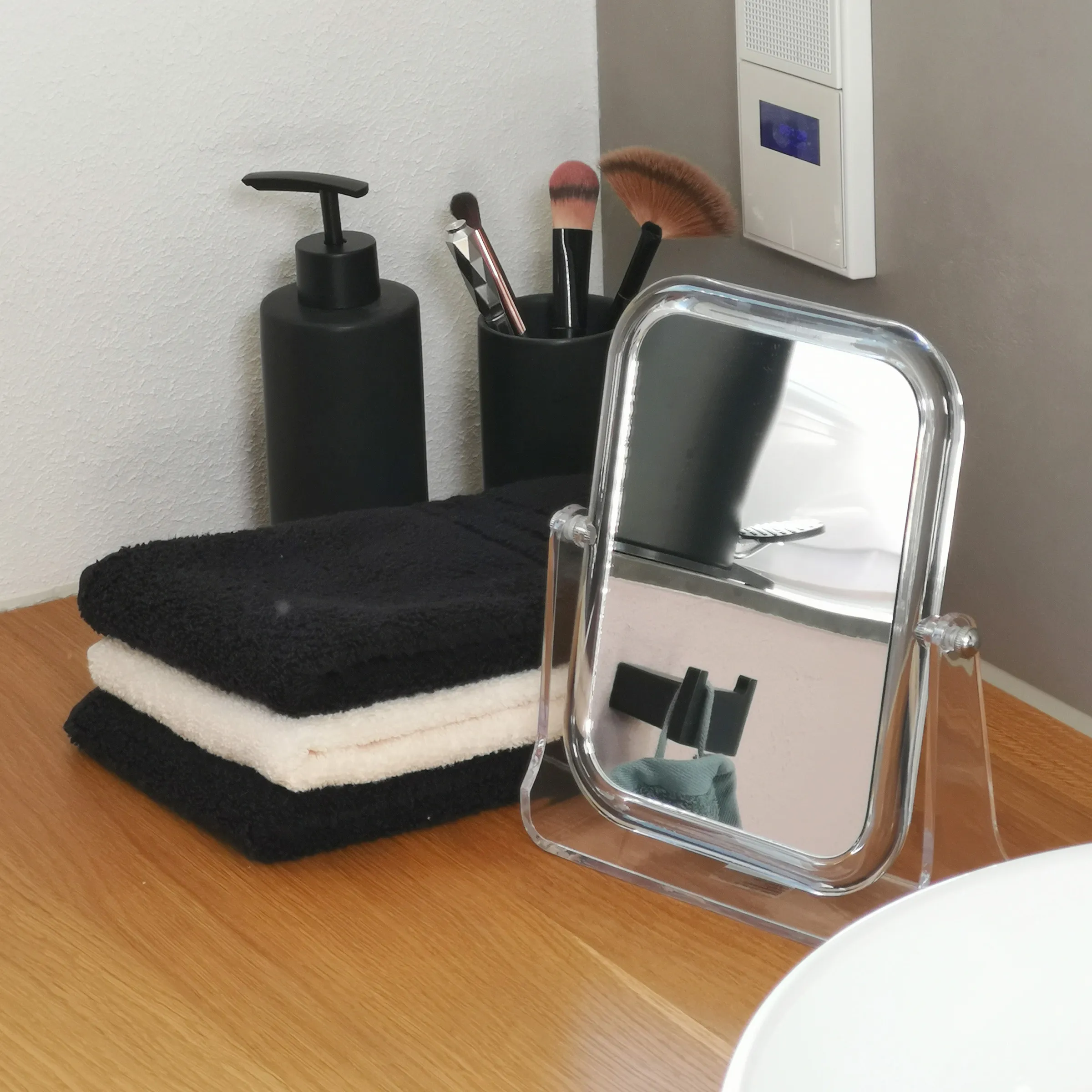 Badezimmer Accessoires Set mit Spiegel und Handtücher Badezimmer-Accessoires-Set mit Spiegeln, Handtüchern, Seifenspender und Make-up-Pinseln auf Holztisch