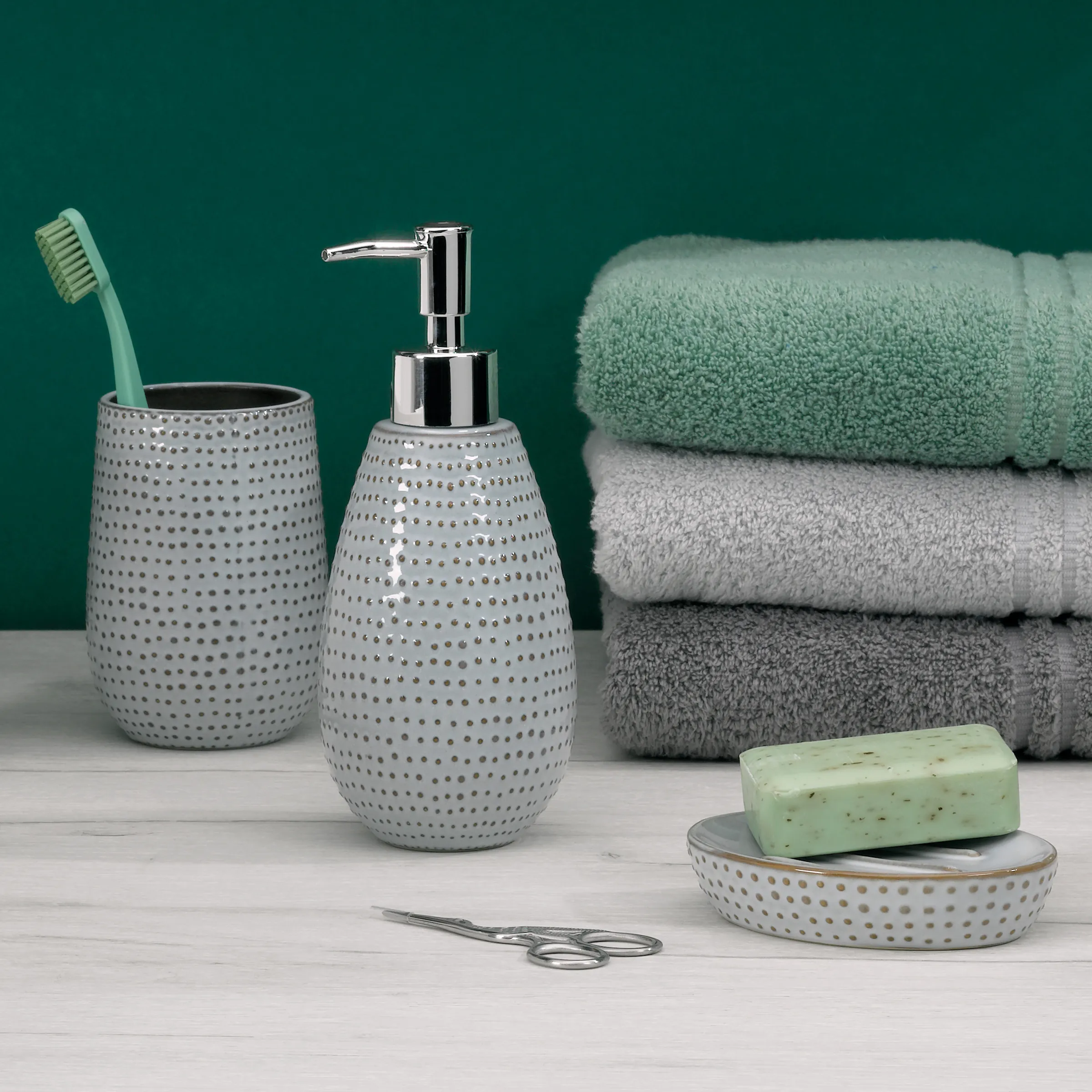 Badezimmer-Accessoires-Set mit Seifenspender, Zahnputzbecher und Seifenschale in grau, dazu Handtücher