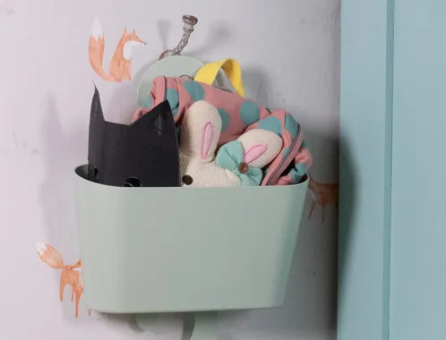 Wandaufbewahrung Kinderzimmer - Pastell Korb mit Kuscheltieren und Spielzeug Pastellfarbener Wandkorb mit Kuscheltieren und Stofftieren für Kinderzimmer an hellblauer Wand