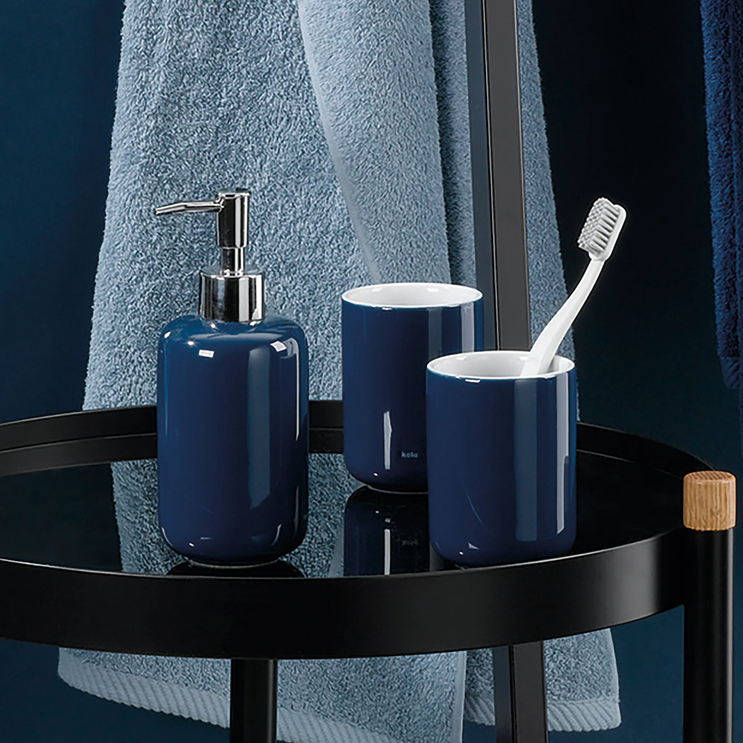 Navy-blaues Badezimmer-Set mit Seifenspender, Zahnputzbecher und Zahnbürste auf schwarzem Tablett vor blauem Handtuch