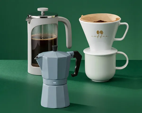 Drei Kaffeezubereiter auf grünem Hintergrund: French Press, Espressokocher und Kaffeefilter mit Tasse