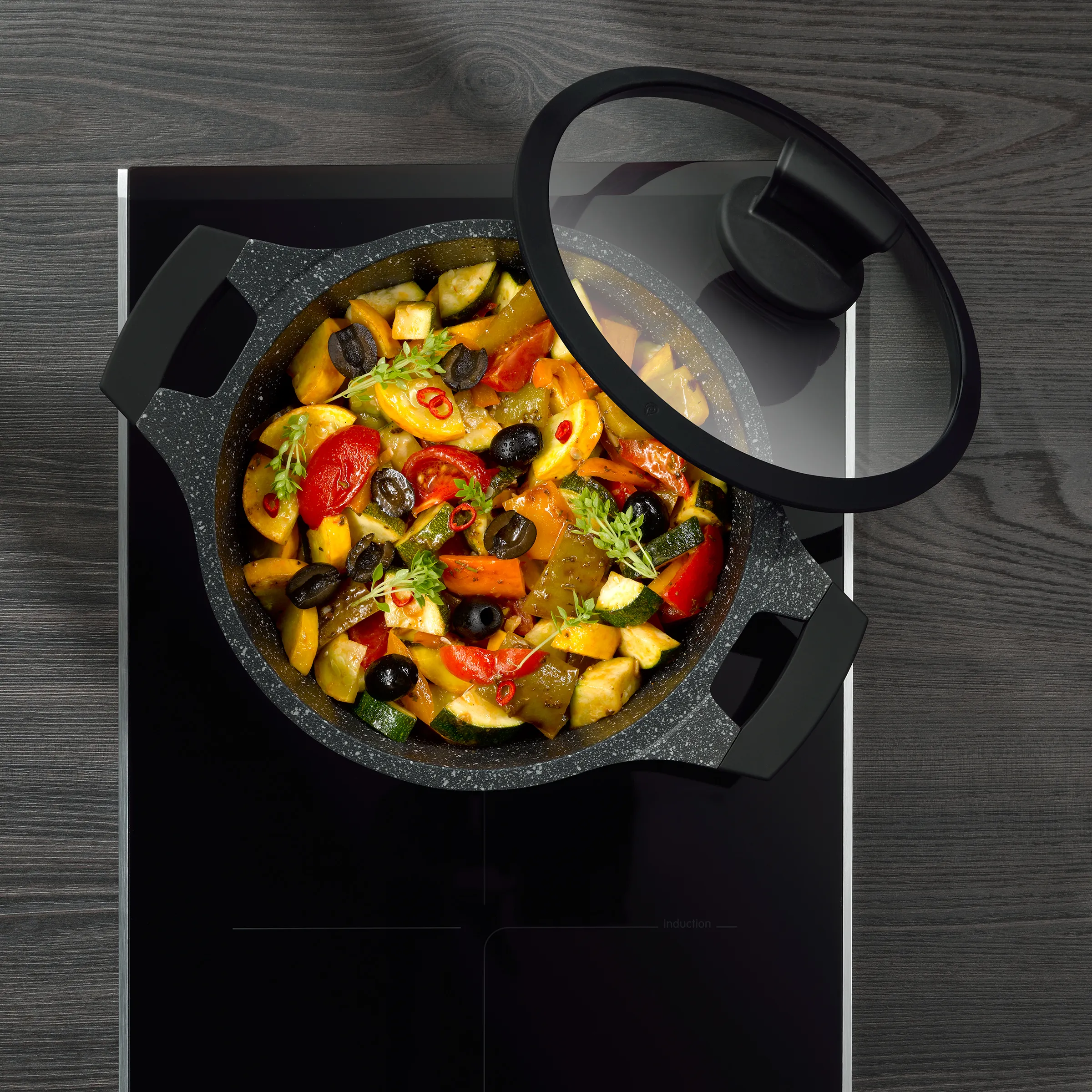 Gemüse-Ragout im Kochtopf - Mediterranes Schmorgericht mit Paprika und Oliven Buntes Gemüse-Ragout mit Paprika, Zucchini, Oliven und Kräutern in schwarzem Kochtopf mit Glasdeckel