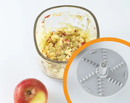 Gemüsereibe und Apfelreibe für Küchengebrauch Küchenreibe mit Raspel-Aufsatz neben geriebenen Äpfeln in Behälter und rotem Apfel