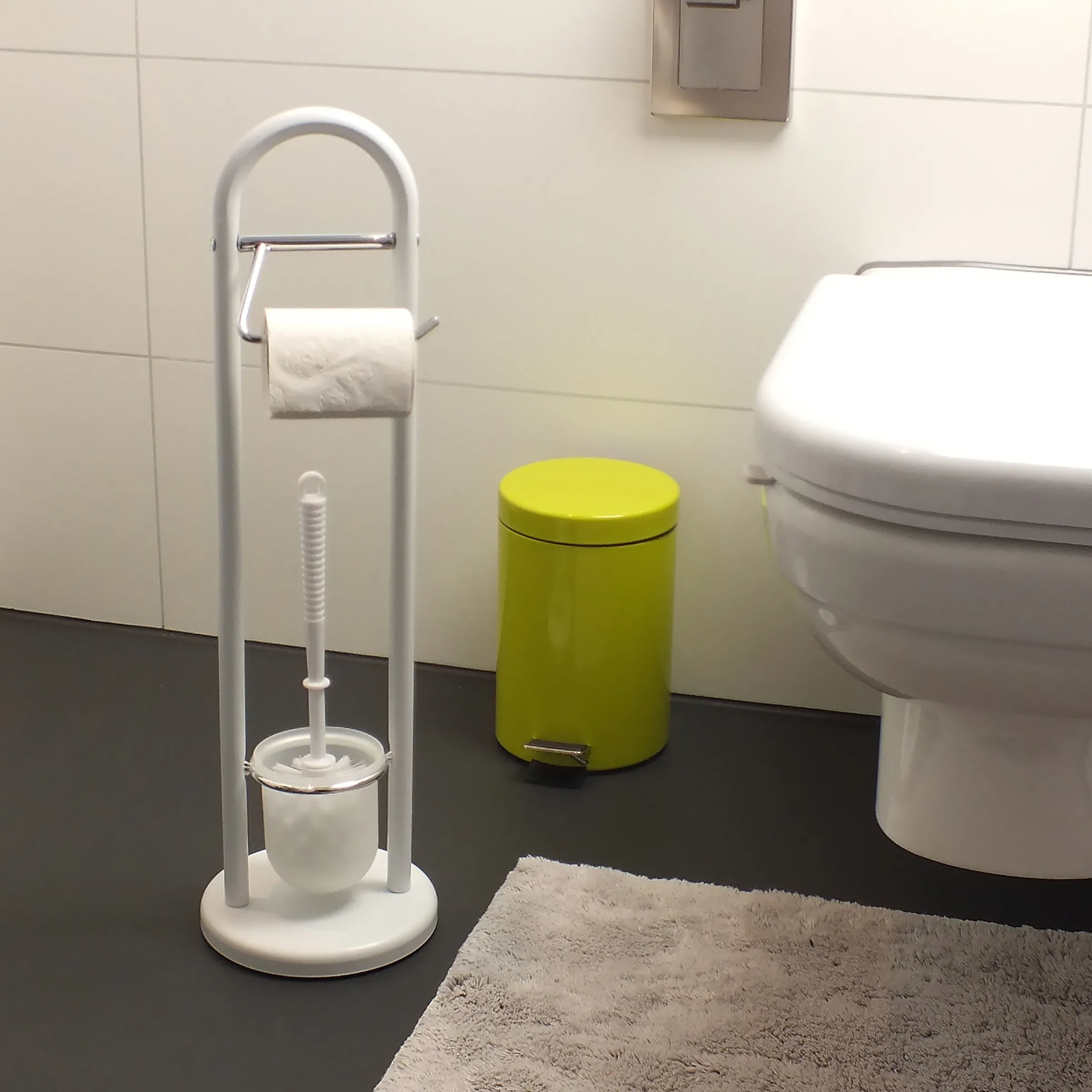 Toilettenzubehör Set: Papierhalter, Bürste und Abfalleimer Badezimmer-Set mit Toilettenpapierhalter, Toilettenbürste und grünem Mülleimer neben weißer Toilette