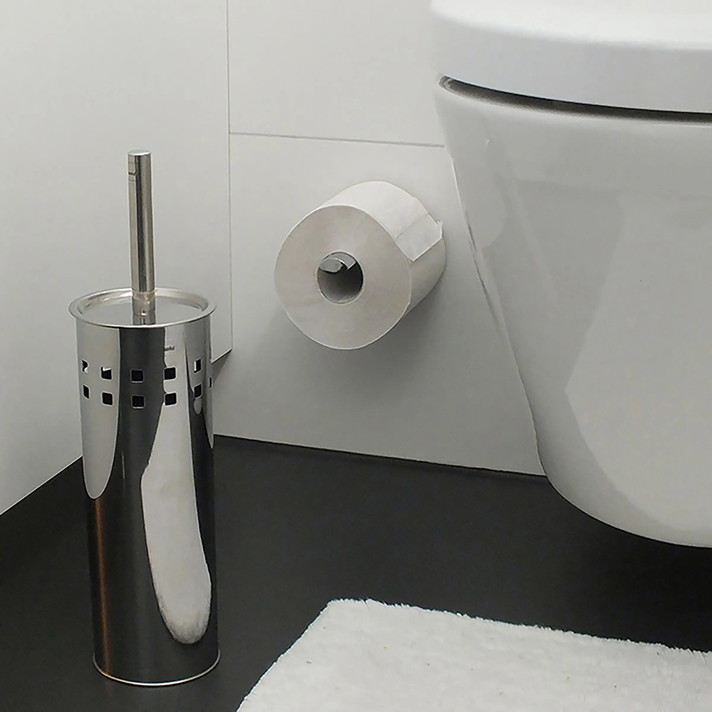 Badezimmer Zubehör Set - Toilettenbürste und Papierhalter Modernes Badezimmer mit schwarzem Boden, weißer Toilette, Toilettenpapierhalter und Toilettenbürste in Edelstahl-Behälter.