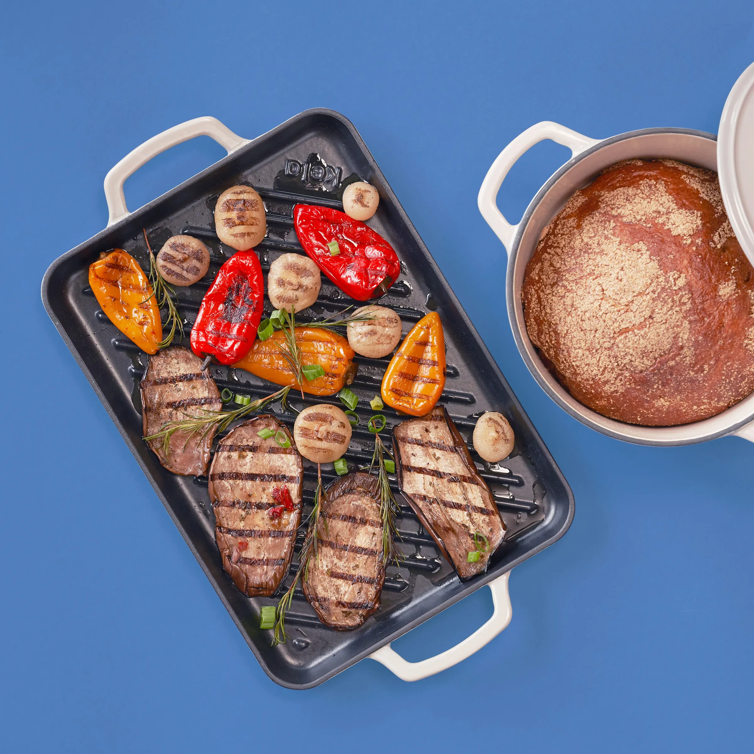Gegrilltes Fleisch mit Gemüse in Grillpfanne - Gesunde Küche Gegrillte Fleischsteaks, Paprika und Champignons auf schwarzer Grillpfanne neben Kochtopf auf blauem Hintergrund