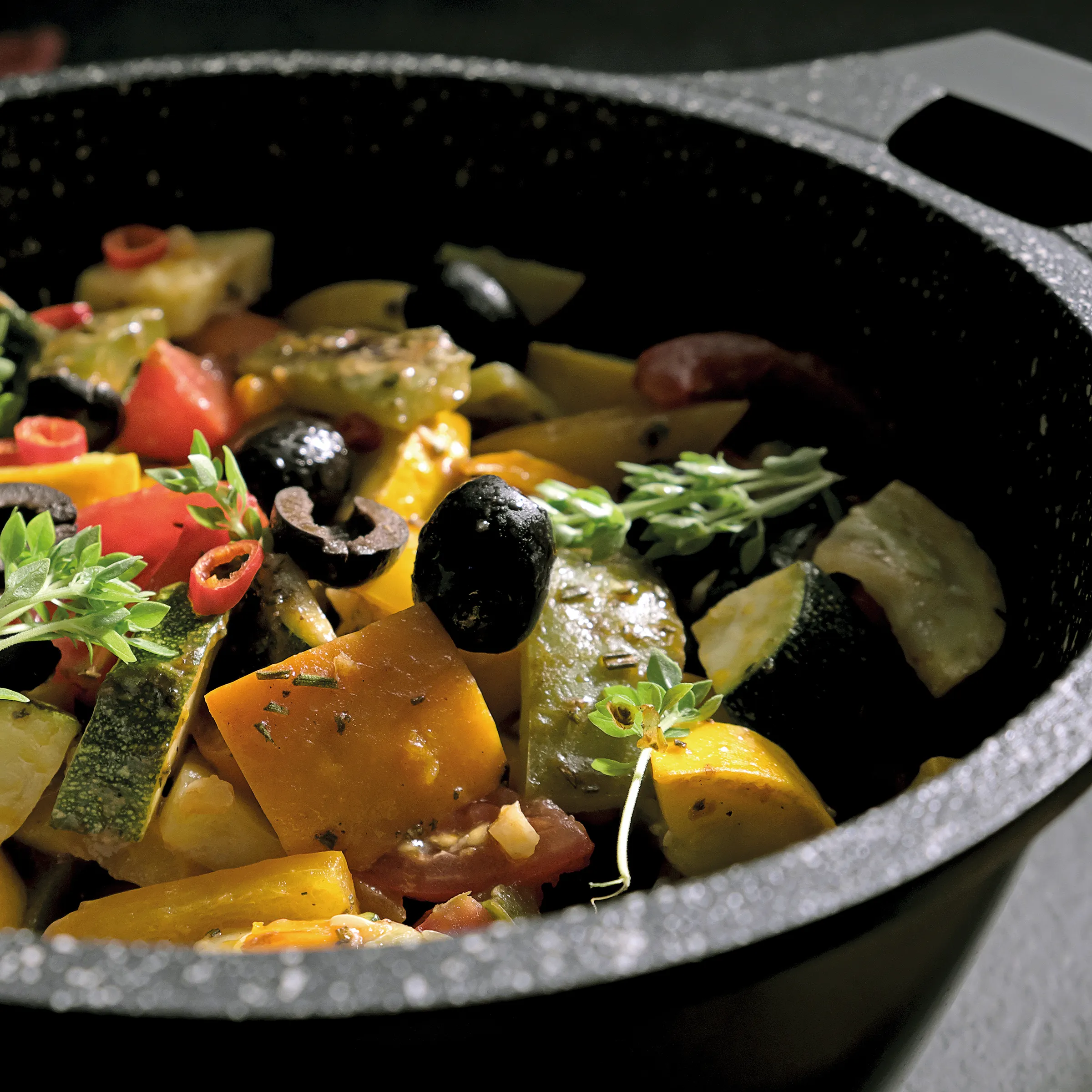 Gemüseeintopf Rezept - Gesundes Gemüse kochen Gemüseeintopf in schwarzem Topf mit Zucchini, Paprika, schwarzen Oliven, Kräutern und Gewürzen