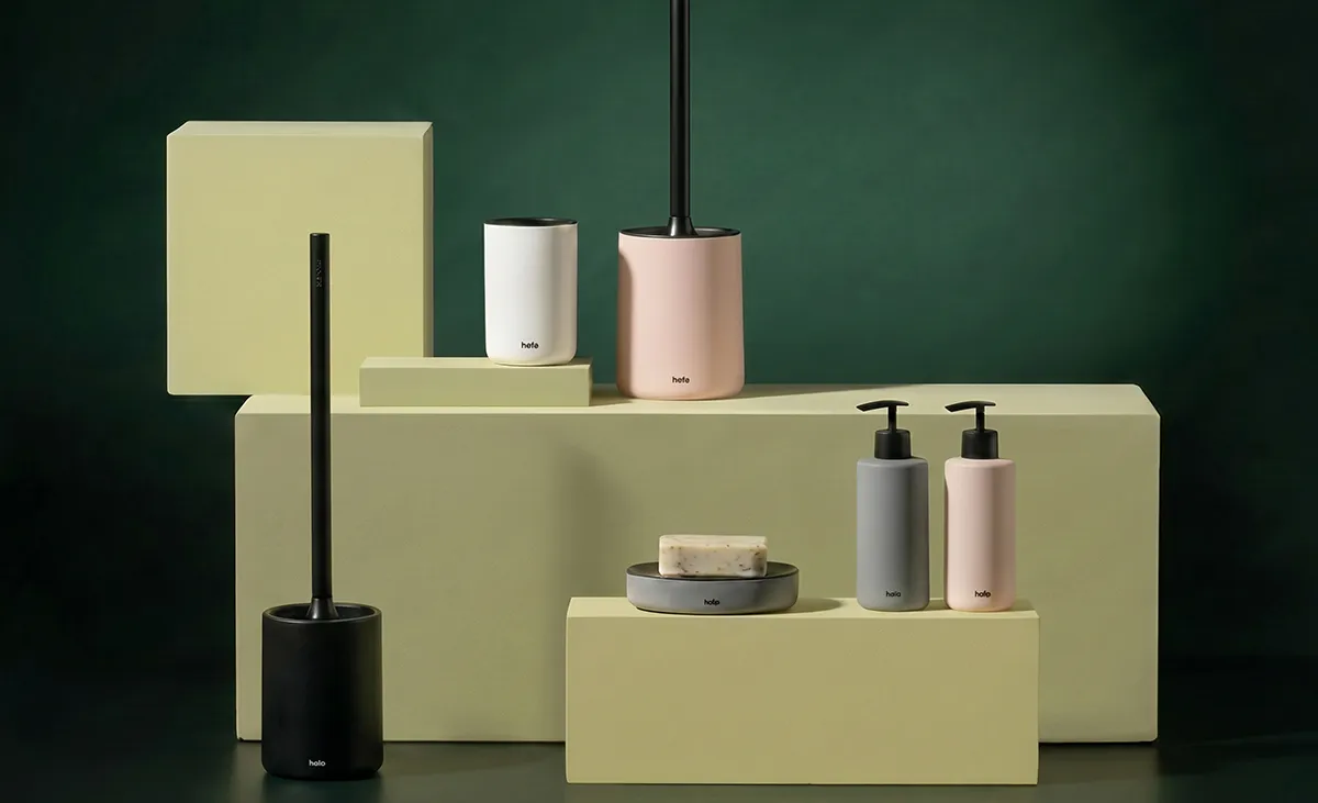 Holo Badezimmer-Accessoires Set - Modernes Design in verschiedenen Farben Badezimmer-Accessoires-Set von holo in Schwarz, Weiß, Grau und Rosa auf gelben Podesten vor grünem Hintergrund