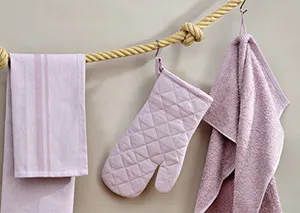 Küchentextilien Set Rosa - Geschirrtücher und Ofenhandschuh Rosa Küchentextilien an Seil: Geschirrtuch, Ofenhandschuh und Handtuch vor beiger Wand