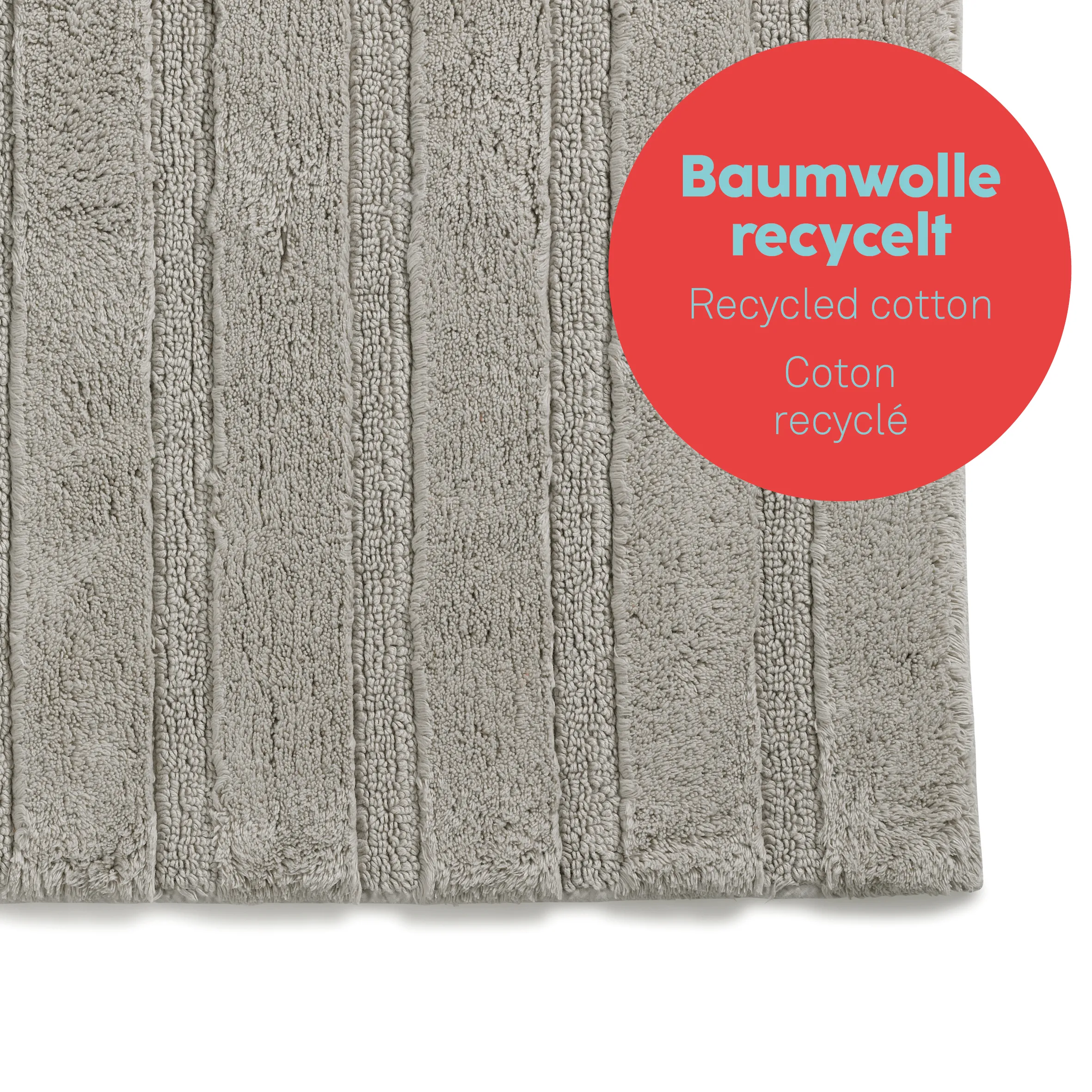 Baumwolle recycelt Teppich – Nachhaltiger grauer Baumwollteppich mit Struktur Grauer Baumwollteppich mit recyceltem Material, Nahaufnahme der strukturierten Oberfläche mit rotem Label
