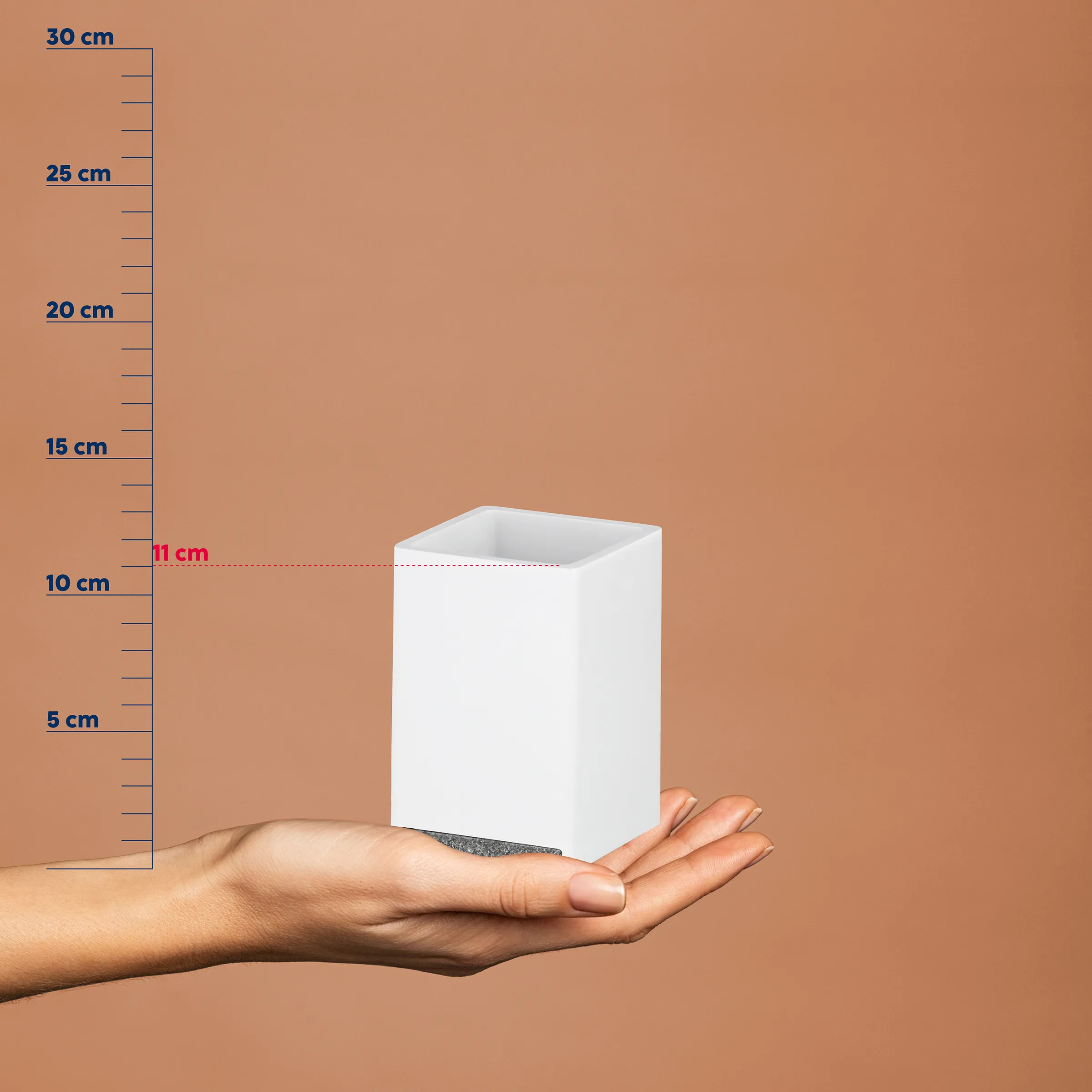 Hand hält weißen rechteckigen Behälter vor beigem Hintergrund mit Maßstab, Höhe ca. 11 cm