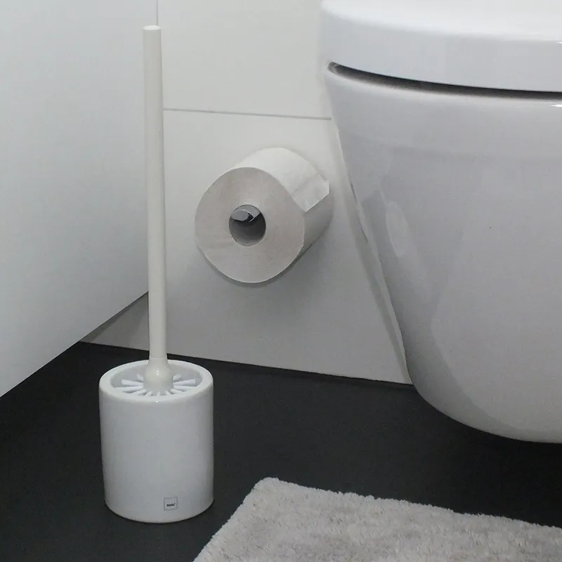 Toilettenbürsten-Set und Toilettenpapierhalter für das Badezimmer Badezimmer-Set mit weißer Toilettenbürste, Toilettenpapierhalter und Rolle neben einer Toilette
