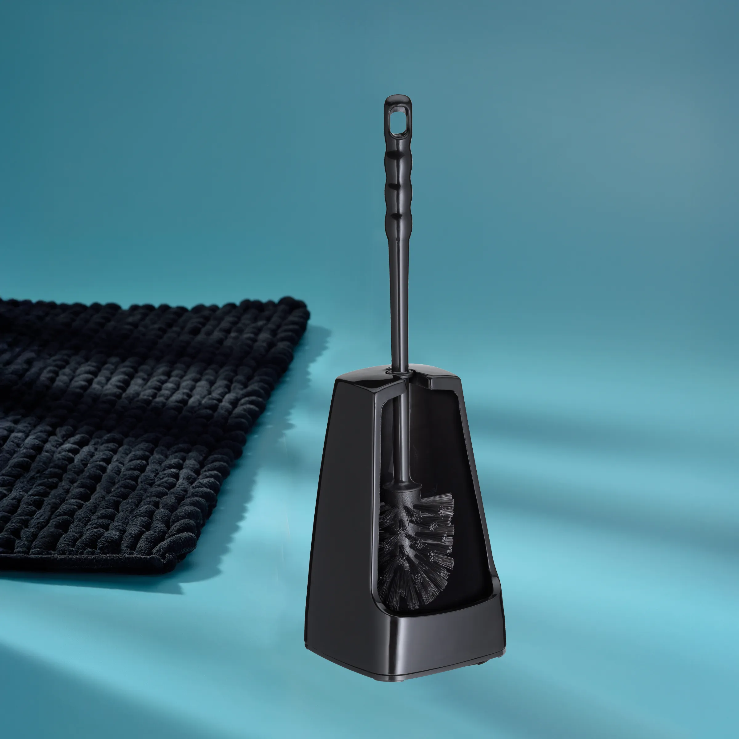 Schwarze Toilettenbürste mit Behälter auf blauem Hintergrund neben dunklem Handtuch