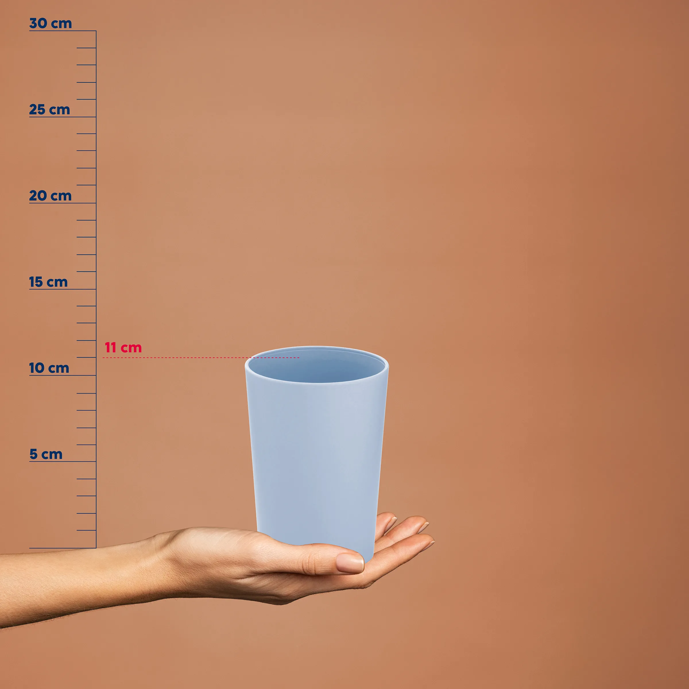 Hellblauer Becher in einer Hand neben einer Messskala, die eine Höhe von 11 cm anzeigt