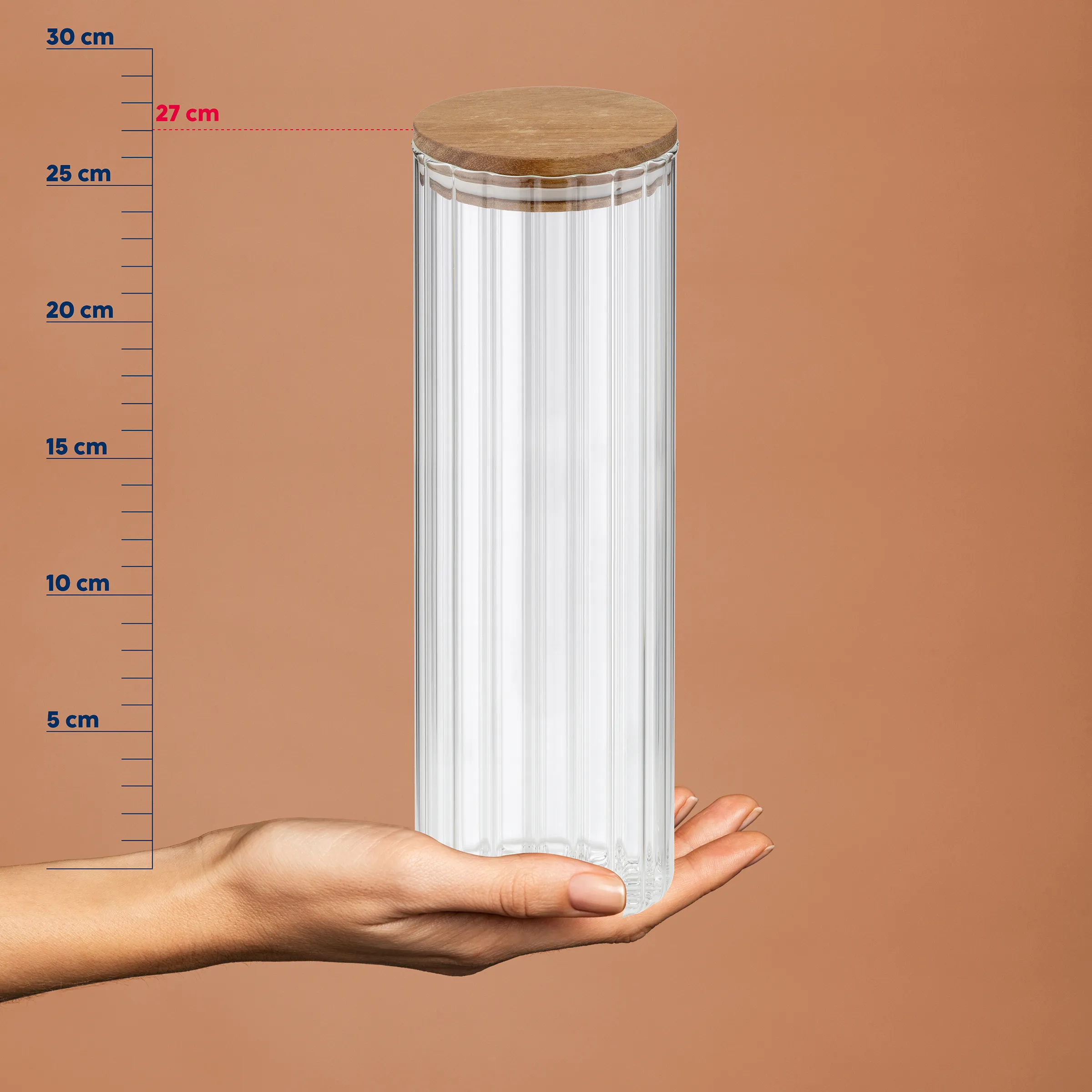 Transparenter Vorratsbehälter mit Holzdeckel auf Hand, Höhe 27 cm, geriffeltes Glasdesign vor Maßstab