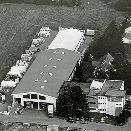 Industrieanlage und Fabrik Lagerhallen Luftaufnahme Luftaufnahme einer Industriefabrik mit großen Lagerhallen, Parkplatz und Bürogebäude neben Bäumen