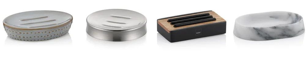Vier verschiedene Seifenschalen aus unterschiedlichen Materialien und Designs: Keramik, Edelstahl, Holz und Marmor nebeneinander dargestellt.