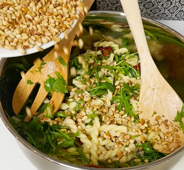 Gesunder Salat mit Rucola, Fenchel und Pinienkernen - Frisches Salatrezept Frischer Salat mit Rucola, Fenchel und gerösteten Pinienkernen in Edelstahlschüssel mit Holzbesteck