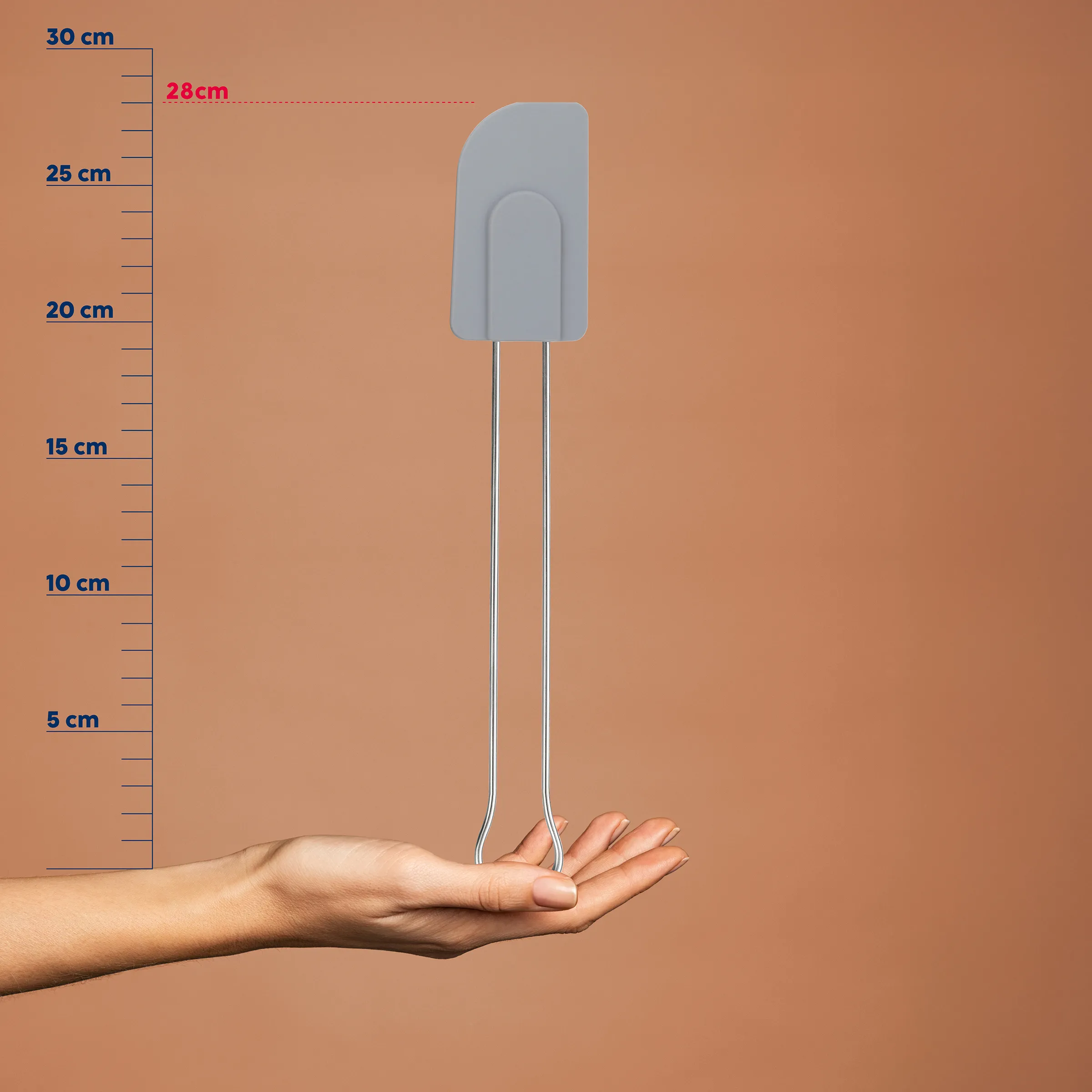 Grauer Silikon-Teigschaber mit langem Griff wird über einer Hand gehalten, Größenskala von 0-30 cm