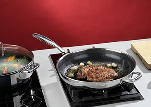 Wok mit Fleisch und Gemüse auf Gasherd, daneben Topf mit dampfender Soße, rotes Küchendesign