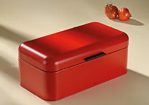 Roter Brotkasten Metall - Stilvolle Brotbox Aufbewahrung für die Küche Roter Brotkasten aus Metall mit geklapptem Deckel, daneben zwei Tomaten auf heller Arbeitsfläche