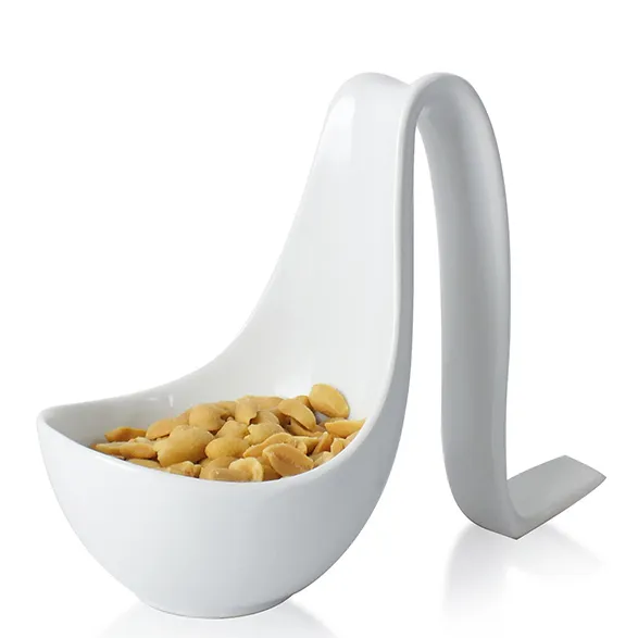 Designer-Snackschale mit Griff - moderne Nussschale weiß Weiße Designer-Schale mit gebogenem Griff gefüllt mit Cashewnüssen auf weißem Hintergrund
