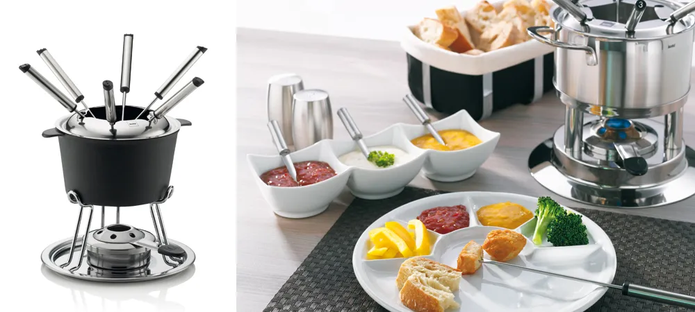 Fondue Set - Komplettes Fondue-Besteck und Zubehör Fondue-Set mit schwarzem Topf, Brenner, Besteck und weißen Schüsseln mit Zutaten sowie Teller mit Fleisch und Gemüse