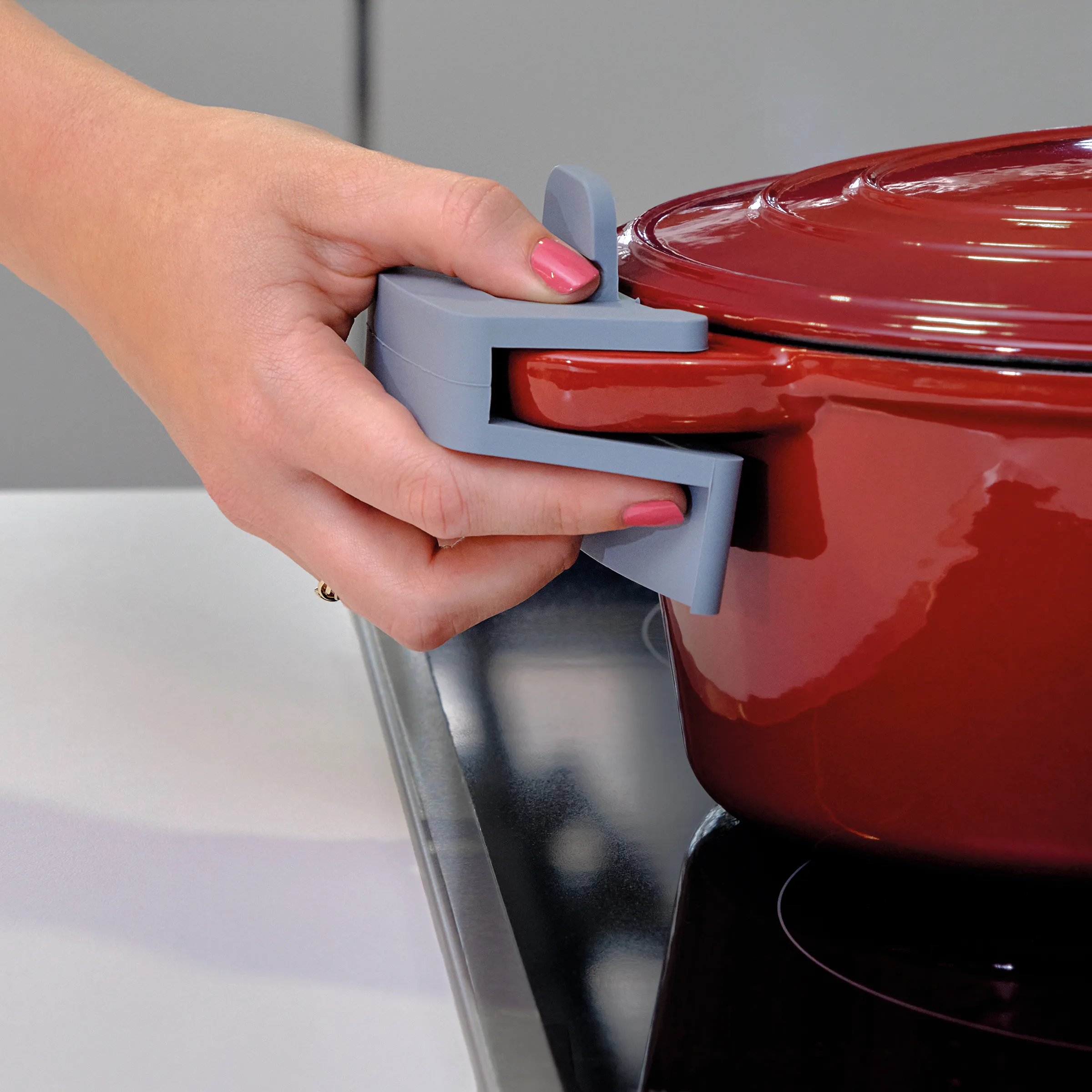 Silikon-Topfgriff für sichere Griffigkeit beim Kochen Hand mit rosa Nagellack öffnet einen roten Topf mit grauem Silikongriff