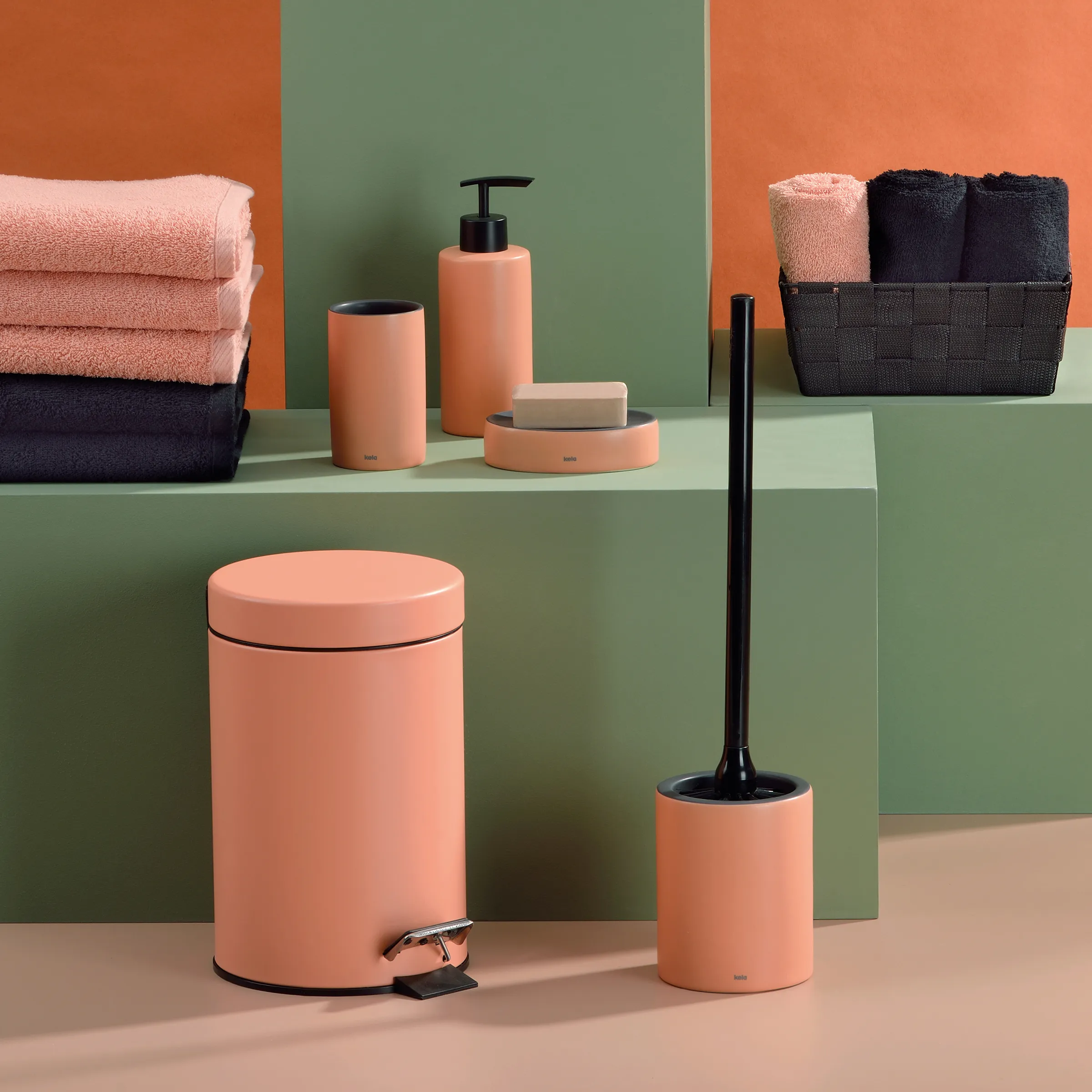 Badezimmer-Set in Koralle mit Treteimer, Seifenspender und Handtüchern Korallenfarbenes Badezimmer-Set mit Treteimer, WC-Bürste, Seifenspender und Handtüchern auf grünem Regal