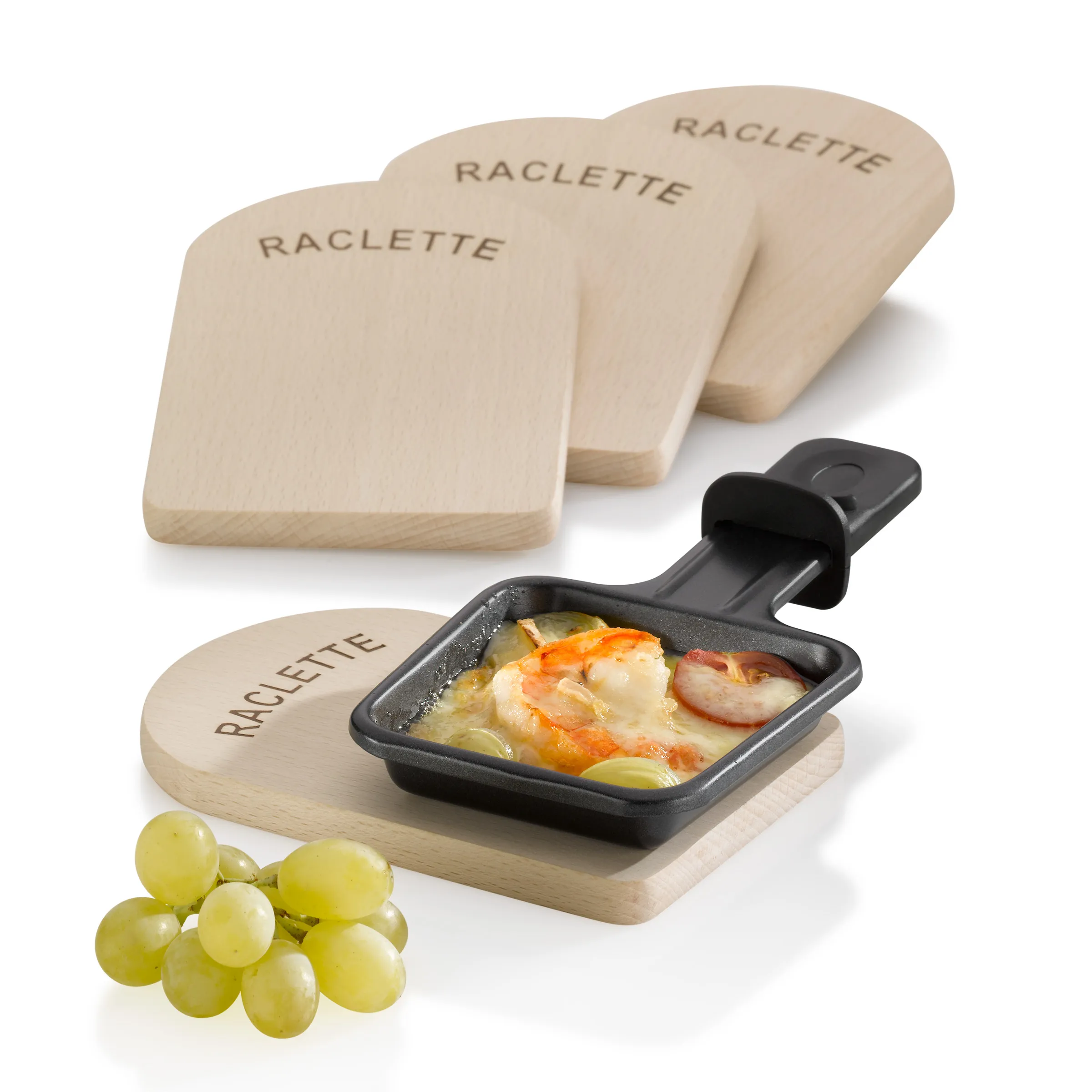 Raclette-Set Holzbretter Käse Servierset Raclette-Set mit vier Holzbrettchen, einer schwarzen Raclette-Pfanne mit Käse und Schinken, sowie grünen Trauben.