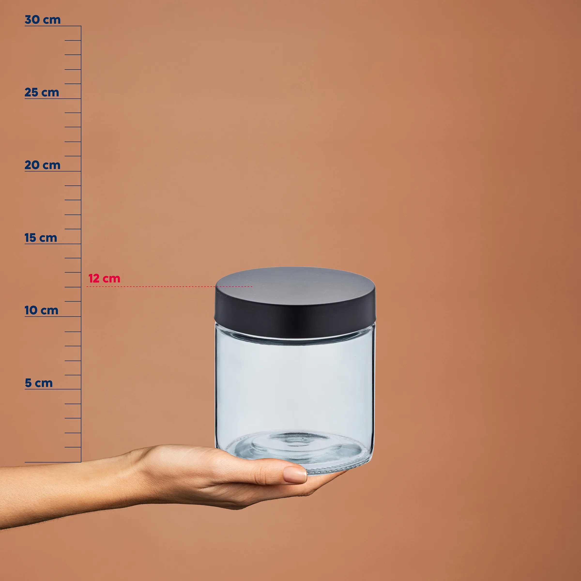 Glasbehälter mit Deckel - Vorratsdose transparent Transparentes Glasgefäß mit schwarzem Deckel auf einer Hand, neben einer Messskala von 5-30 cm. Radius 12 cm markiert.