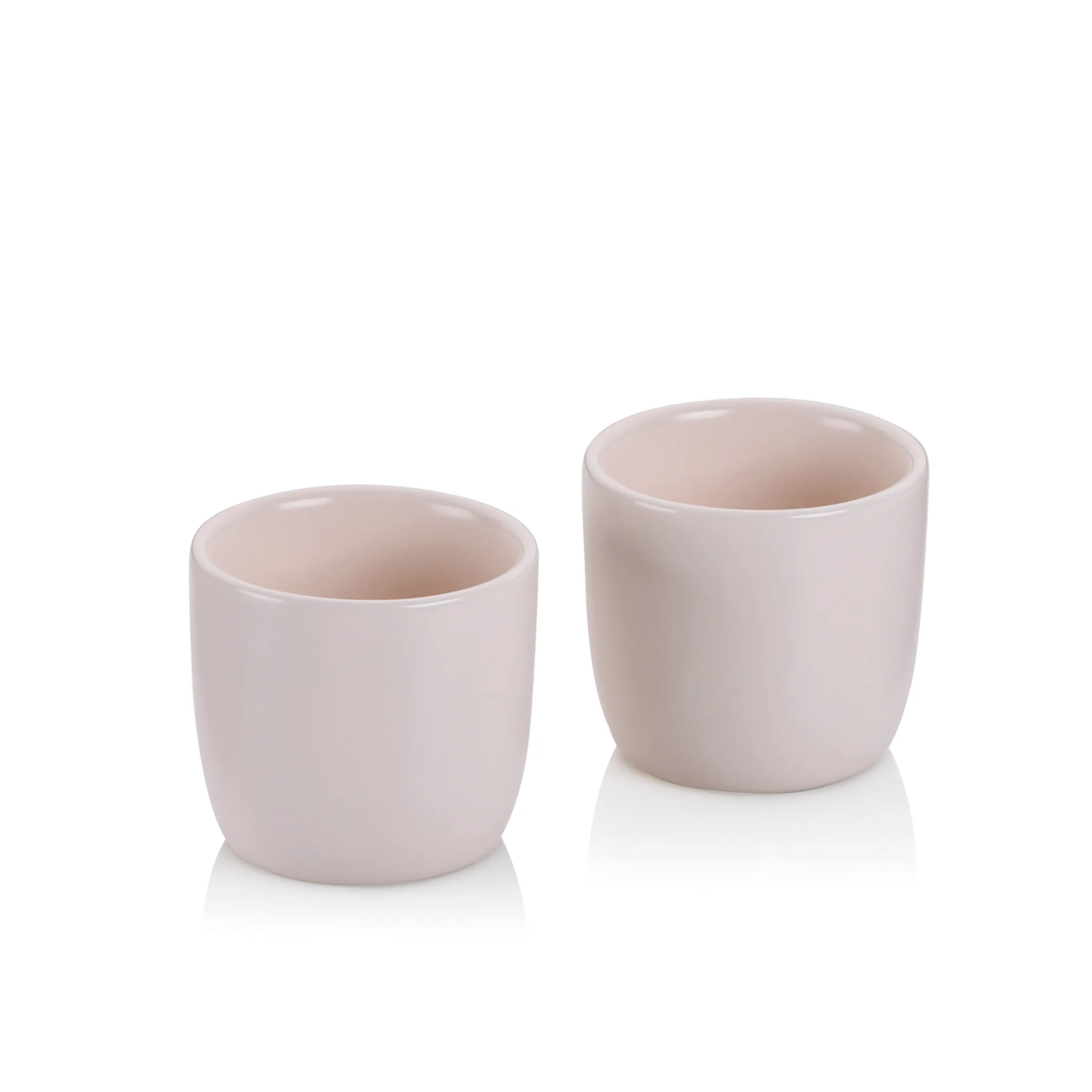 Pastellrosa Keramikbecher Set - Moderne Tassen ohne Henkel Zwei pastellrosa Keramikbecher in unterschiedlichen Größen auf weißem Hintergrund mit Spiegelung