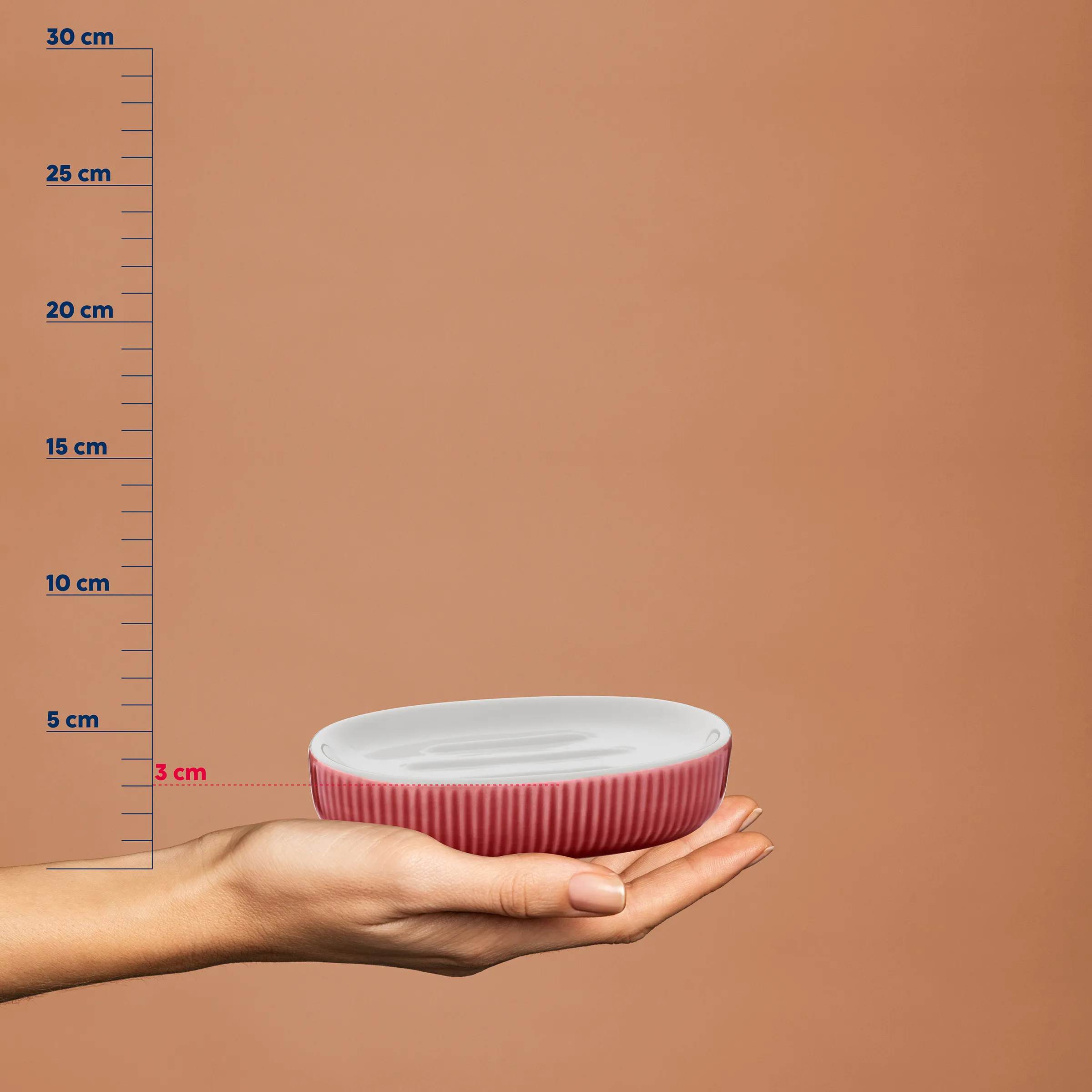 Rosa Schale mit weißem Innenglasur in einer Hand vor Größenvergleichsskala, Höhe etwa 3 cm