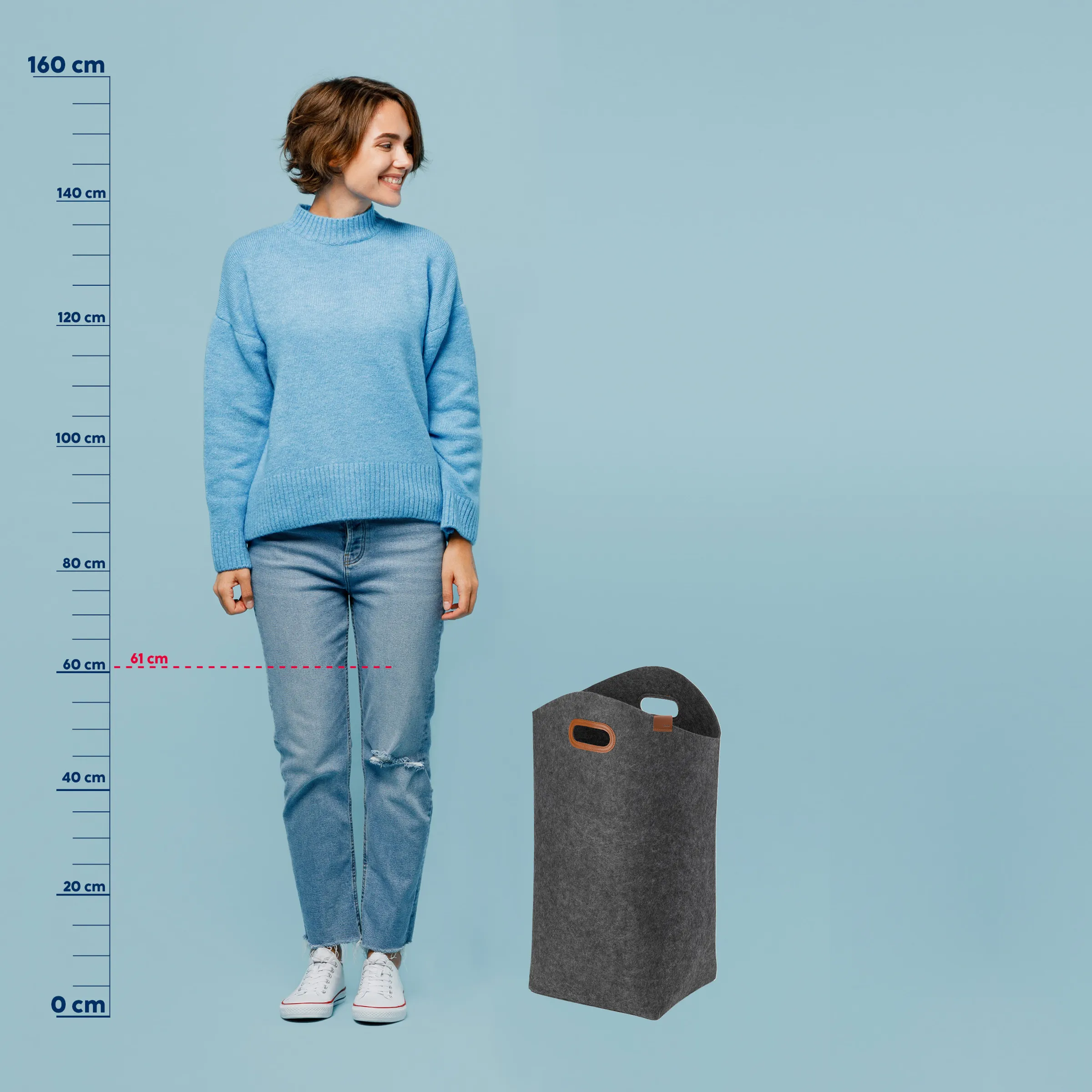 Wäschekorb grau - Größenvergleich und Produktansicht Frau mit blauem Pullover und Jeans neben grauem Wäschekorb mit Griffen, Größenvergleich mit Maßstab