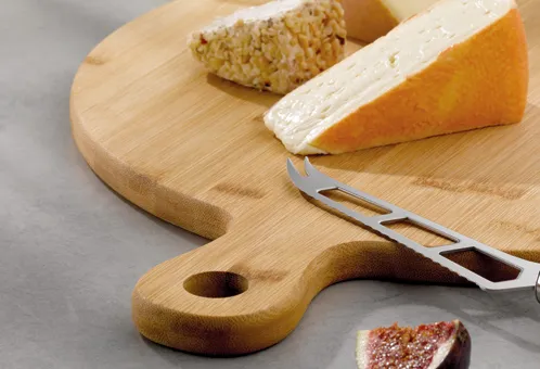 Käsebrett mit Käsemesser - Käseservier-Set Holzbrett mit verschiedenen Käsesorten und Käsemesser auf grauem Untergrund
