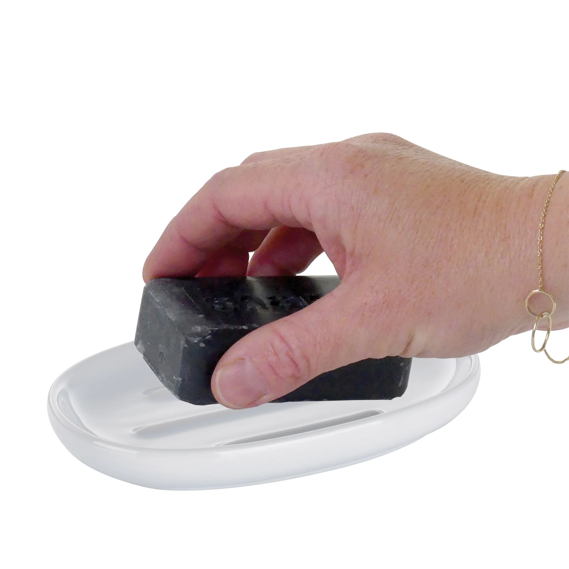 Hand hält schwarze Seife über weißer Seifenschale