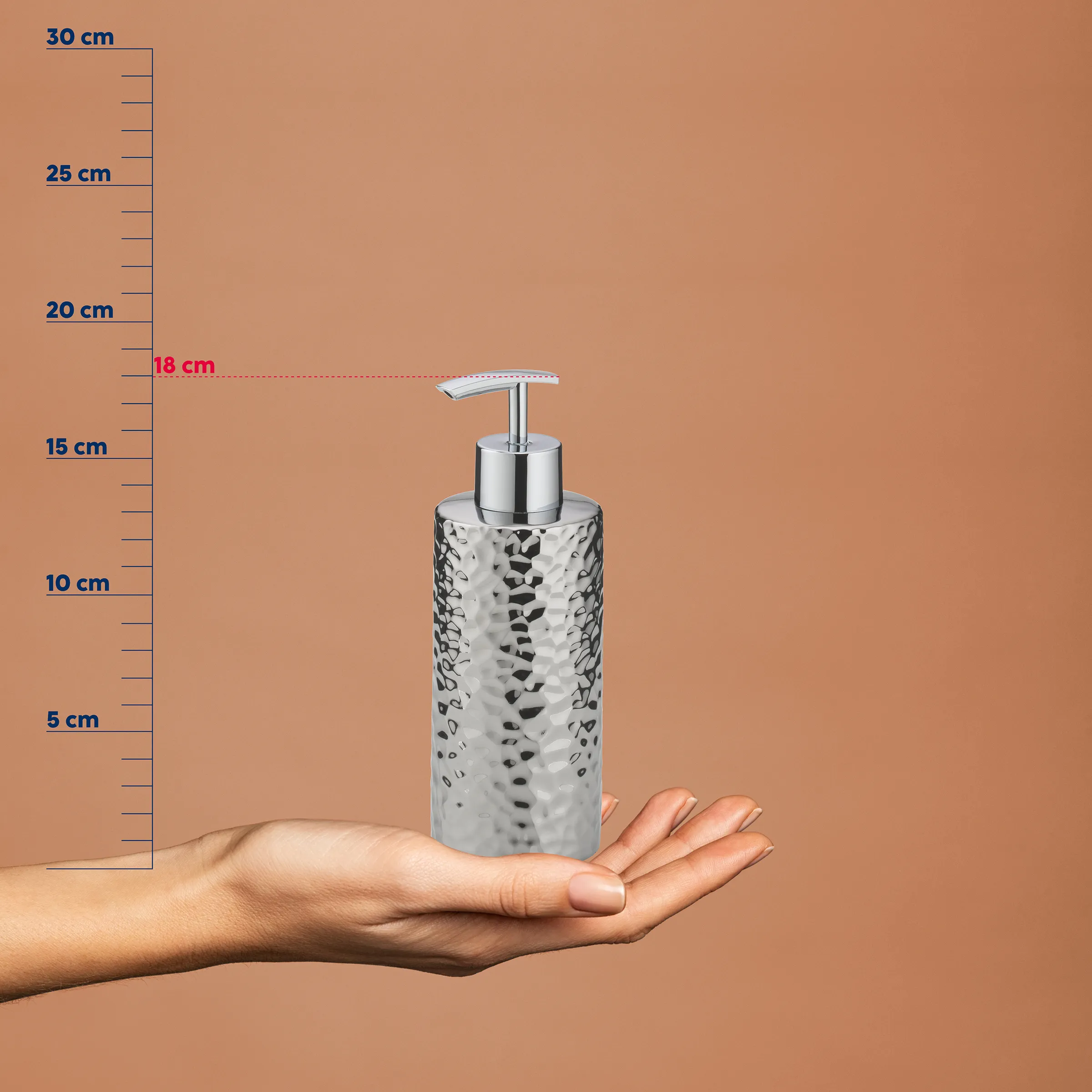 Seifenspender Chrom gehämmert 18 cm - Design Badezimmer Accessoire Verchromter Seifenspender mit gehämmerter Oberfläche auf Hand, Größenangabe 18 cm, vor beigem Hintergrund