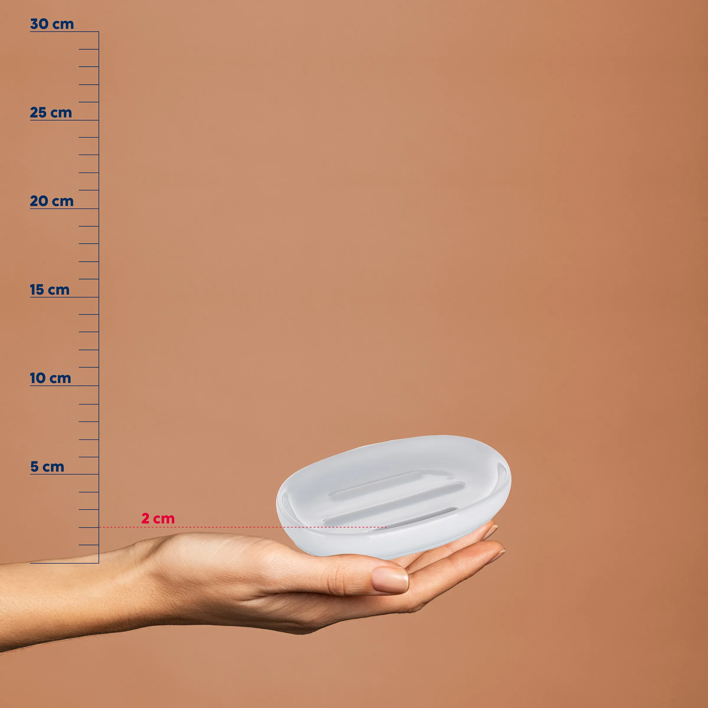 Seifenschale oval weiß klein kompakt Weiße ovale Seifenschale in einer Hand vor einer Messskala, etwa 2 cm Höhe