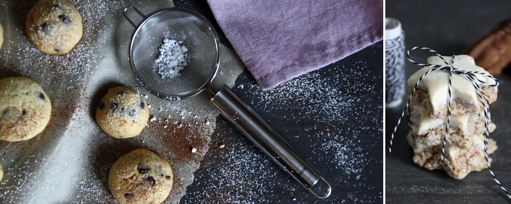 Frisch gebackene Muffins mit Puderzucker bestäubt auf Backblech neben Küchenutensilien und verpackten Keksen
