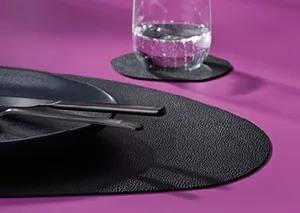 Schwarze glänzende Schuhspitze auf violettem Hintergrund mit Wasserglas darauf