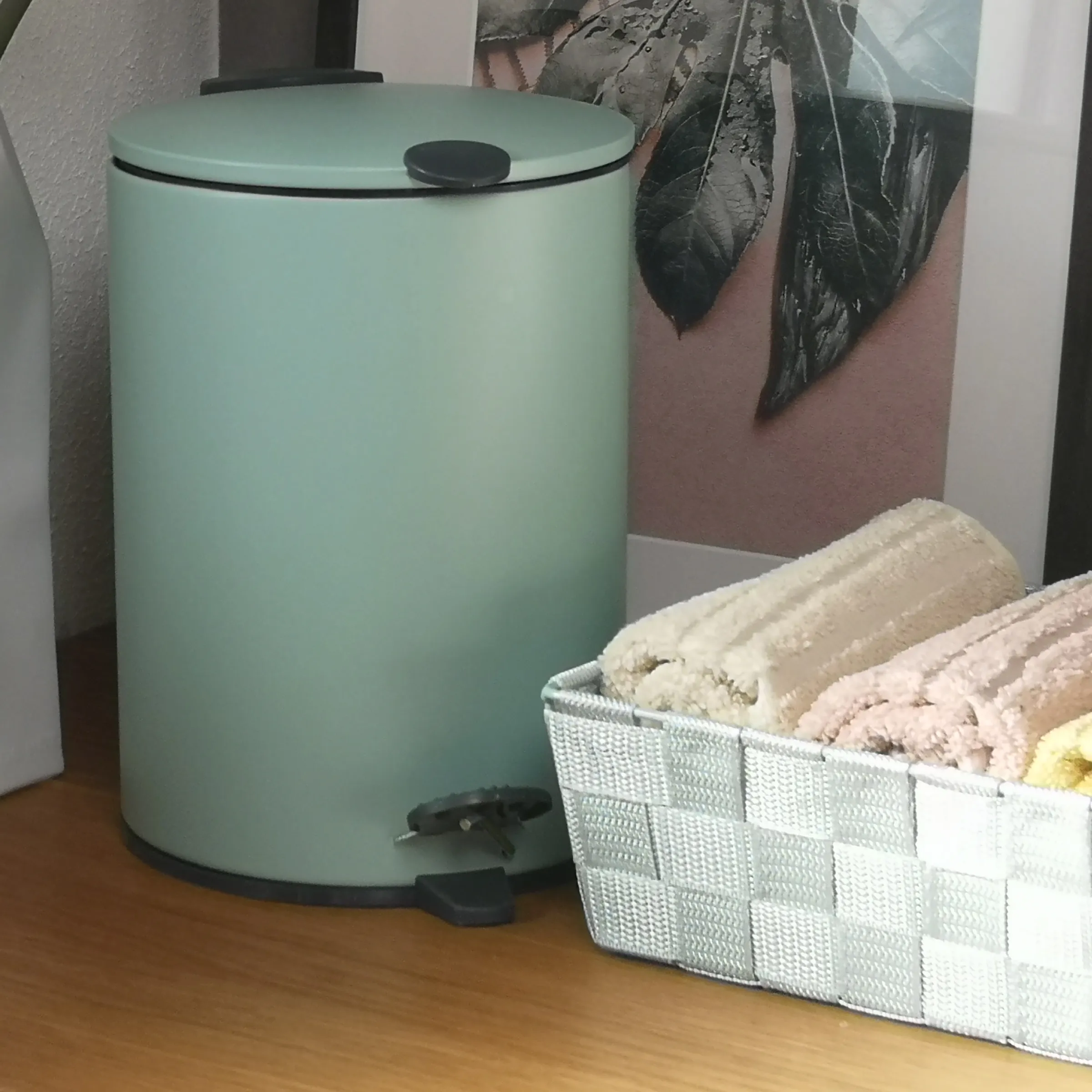 Tretmülleimer mintgrün mit Aufbewahrungskorb Badezimmer Mintgrüner Tretmülleimer und weißer Korb mit beigen Handtüchern auf Holzboden vor rosa Wand