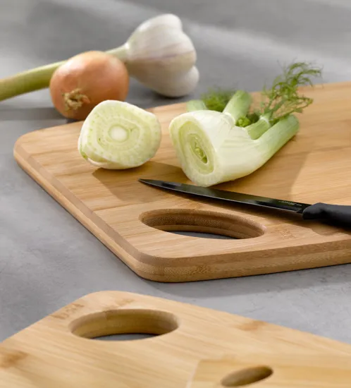 Holzschneidebretter mit frischem Gemüse - Fenchel und Küchenzubehör Frisches Gemüse auf zwei Holzschneidebrettern mit Messer, Fenchel halbiert, Zwiebel und Knoblauch im Hintergrund