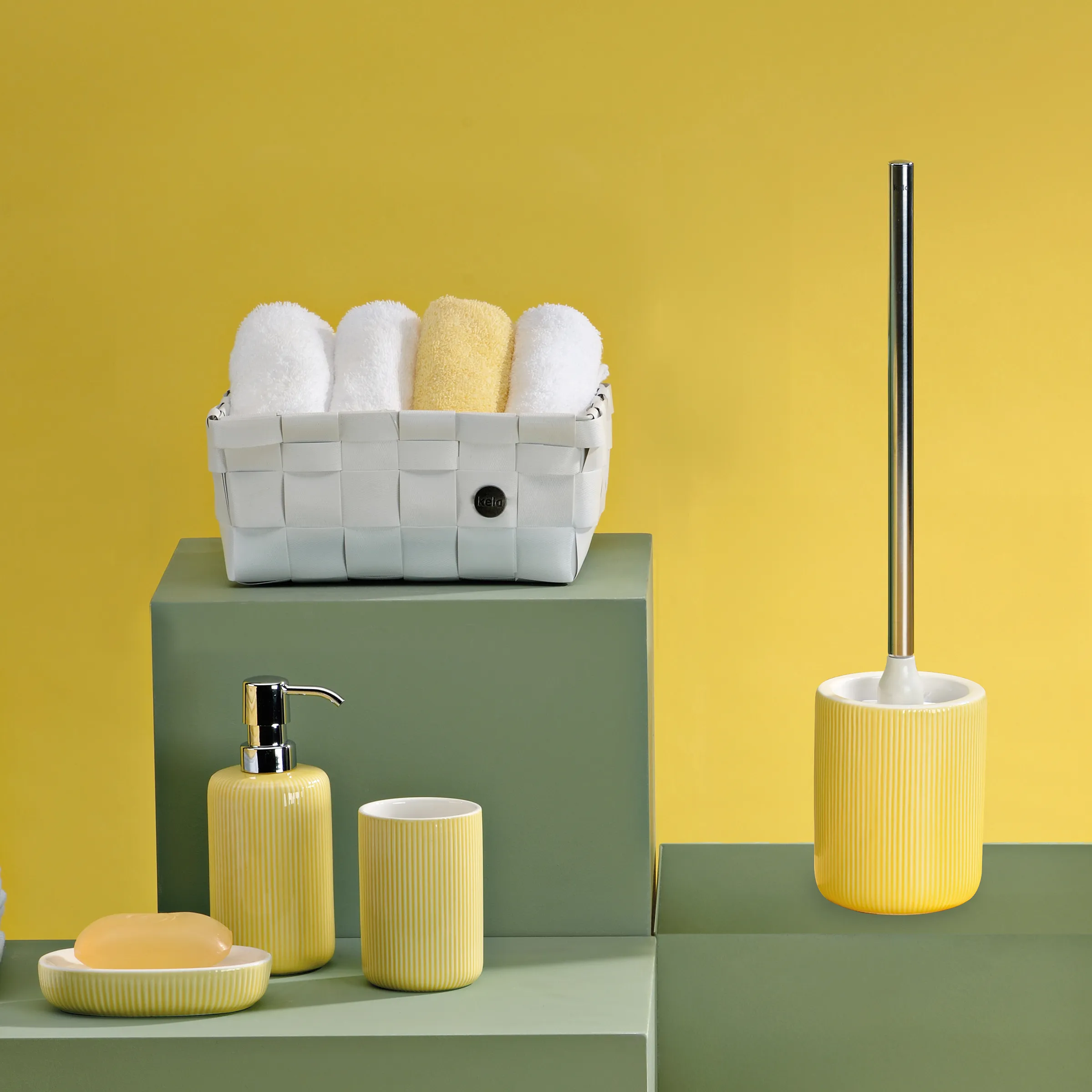 Gelbes Badezimmer-Set mit Seifenspender, Becher, Seifenschale, WC-Bürste und weißem Handtuchkorb
