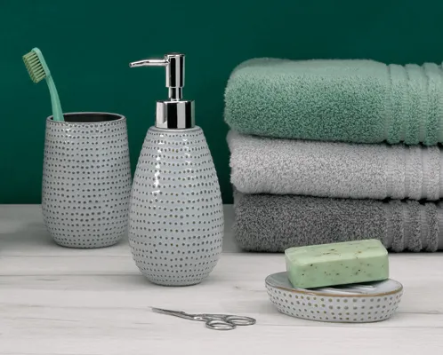Badezimmer-Set mit grauer Keramik-Seifenspender, Zahnbürstenhalter, gestapelten Handtüchern, Seifenschale und Schere