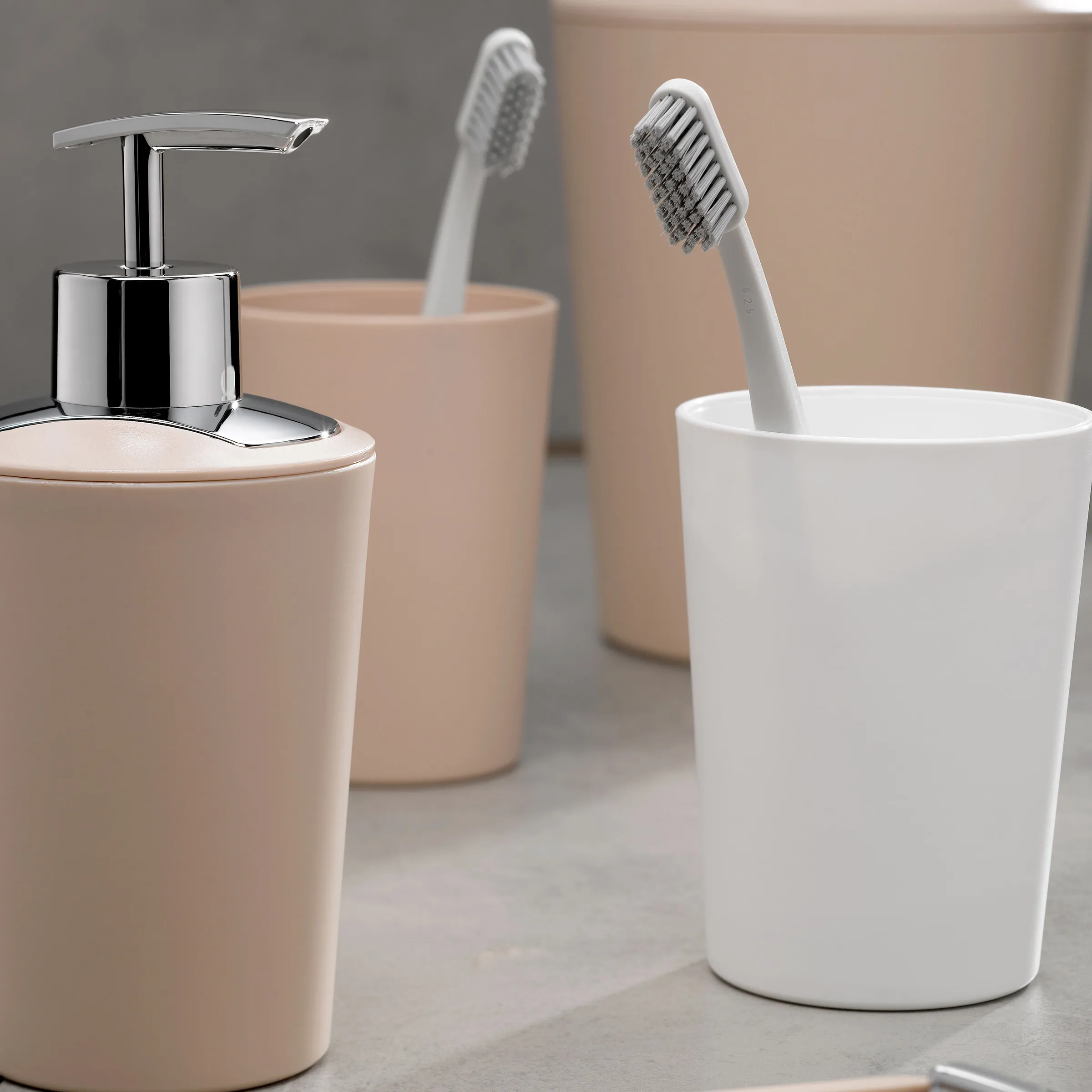 Moderne Badezimmer-Accessoires mit Seifenspender und Zahnbürstenhalter in Beigetönen und Weiß