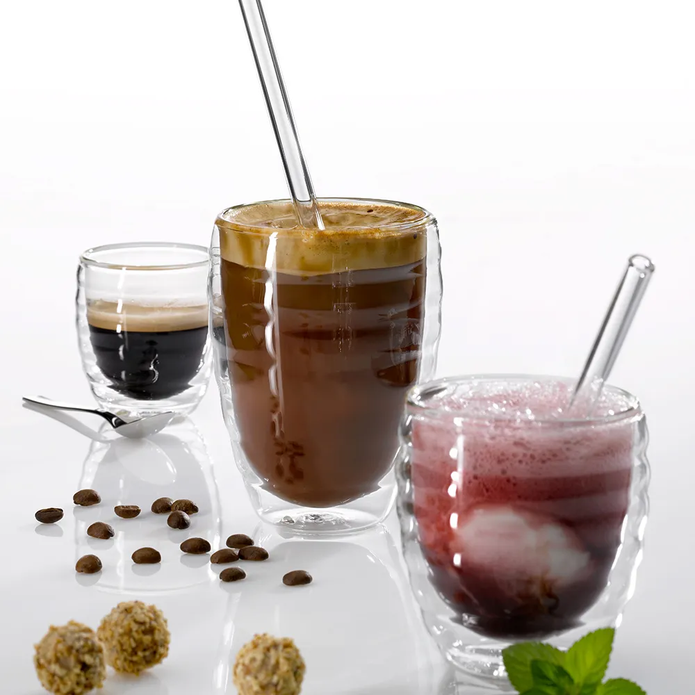 Kaffee und Getränke Assortiment - Doppelwand Gläser Drei Getränke in Doppelwand-Gläsern: Espresso, kalter Kaffee mit Strohhalm und rote Fruchtlimonade mit Minze. Kaffeebohnen und Zutaten sichtbar.