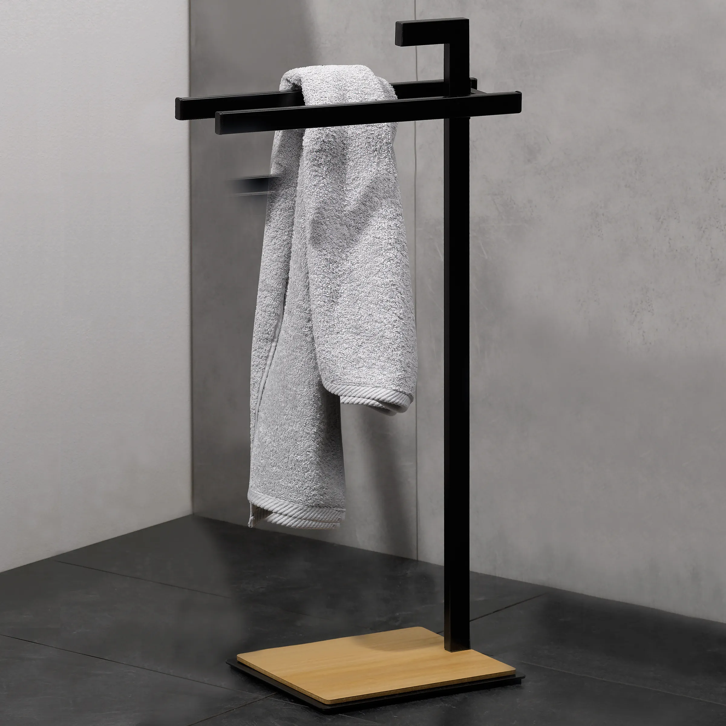 Handtuchständer schwarz mit Holzbasis - modernes Badezimmer Accessoire Schwarzes Handtuchständer-Gestell mit Holzsockel, zwei graue Handtücher über horizontaler Stange hängend