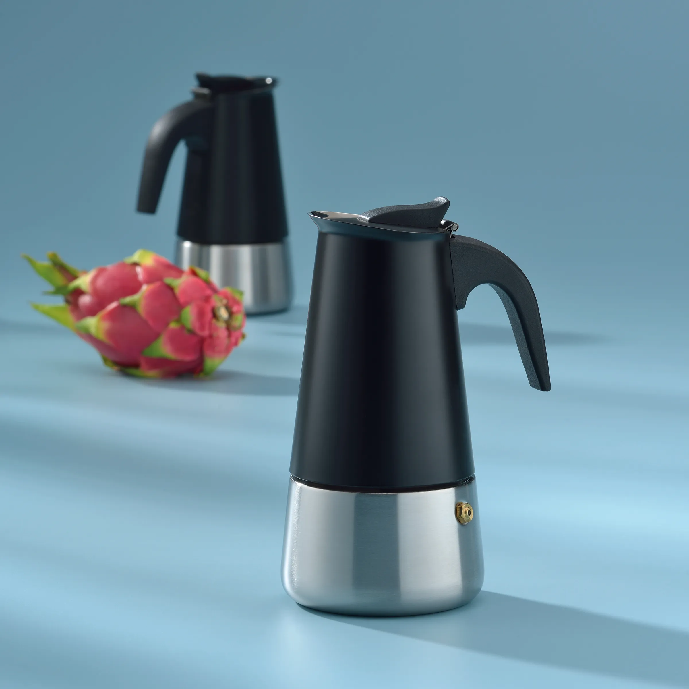 Espressokocher Edelstahl schwarz - Moderne Moka-Kanne für italienischen Kaffee Schwarze Espressokocher aus Edelstahl mit Drachenfrüchten auf blauem Hintergrund