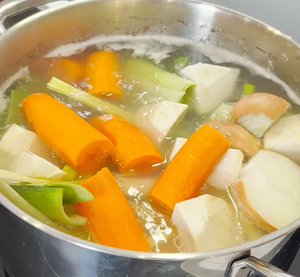 Gemüsebrühe kochen mit frischem Suppengemüse - Karotten, Sellerie und Lauch Gemüsebrühe mit Karotten, Sellerie und Lauch in einem Edelstahltopf auf dem Herd