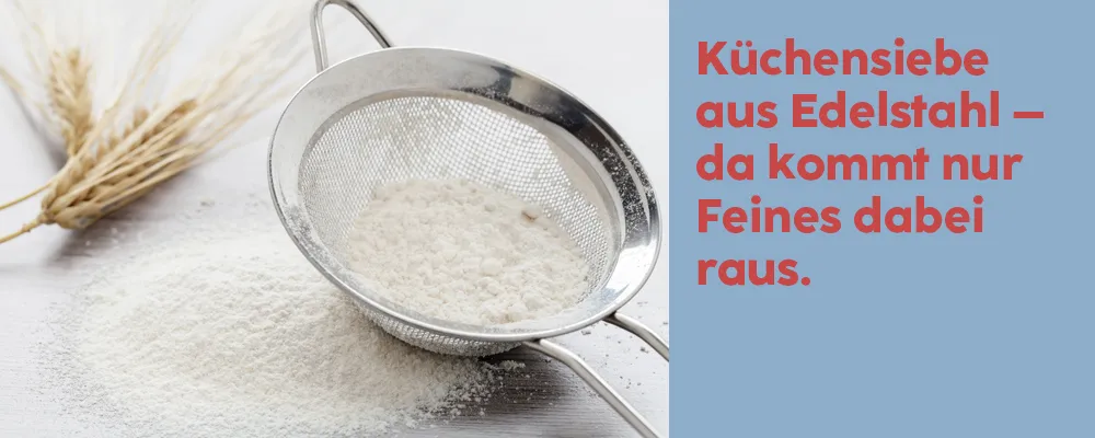 Küchensieb aus Edelstahl zum Mehl sieben – Backzubehör Edelstahl-Küchensieb mit feinem Mehl auf weißer Arbeitsplatte neben Weizenähren
